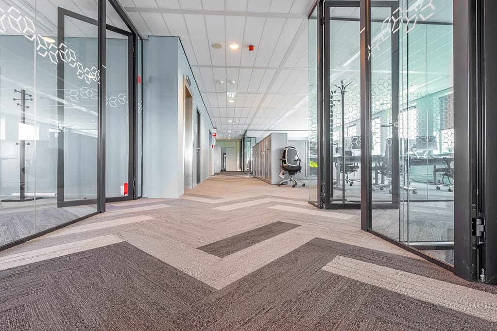 Spacious and bright modern office hallway with glass partitions and contemporary design.